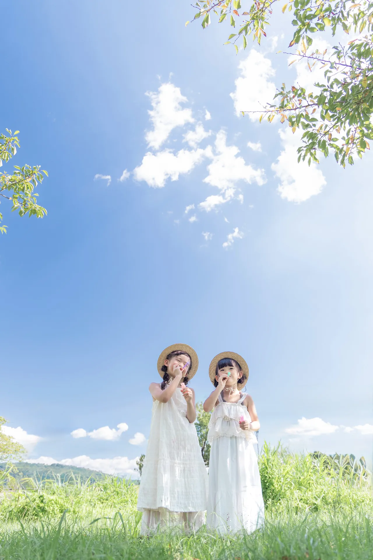 青空の下で、白いワンピースの二人が並んでいる写真