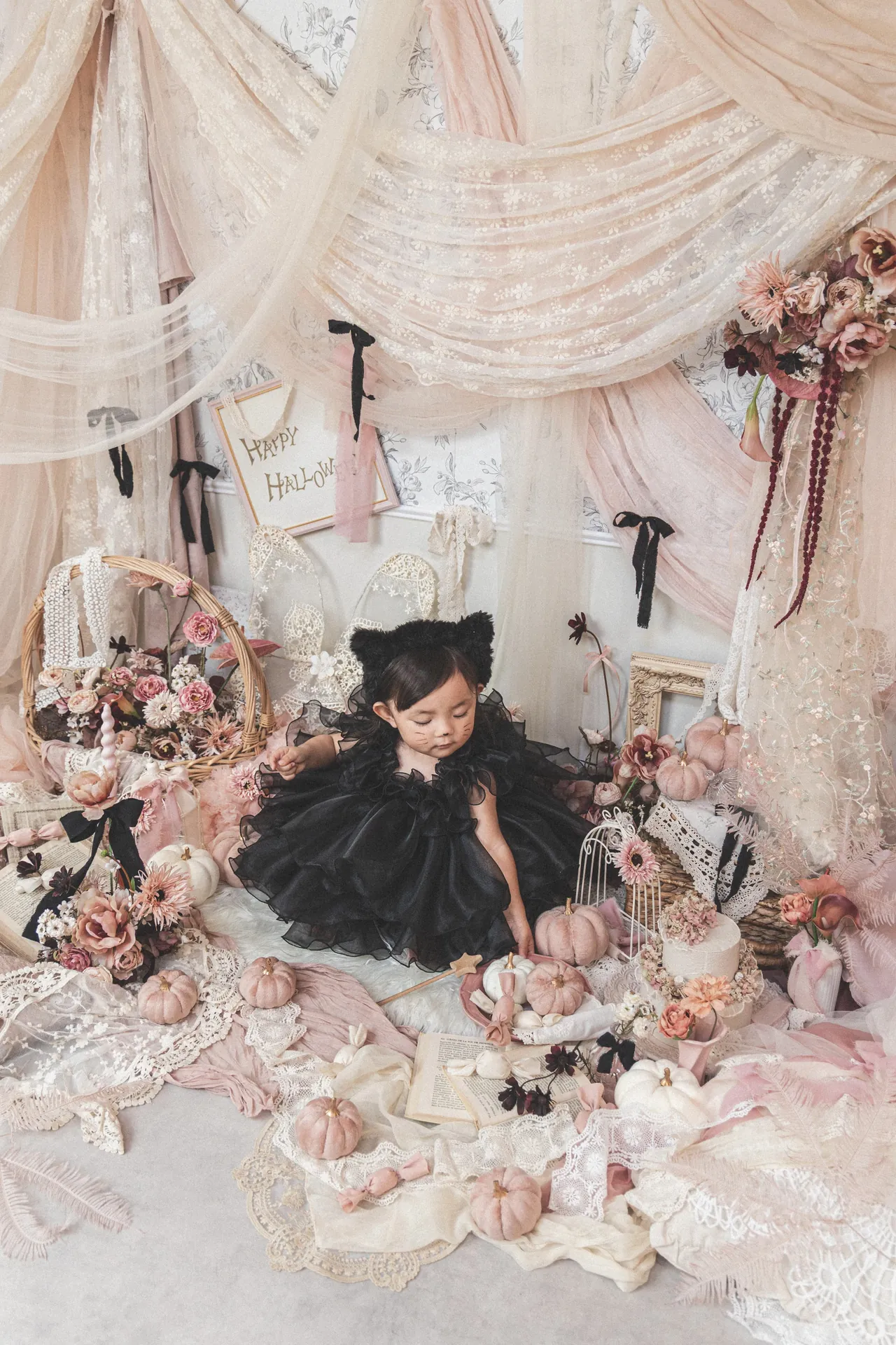 ハロウィンの飾りのセットで、ねこ耳と黒いドレスの女の子が座っている写真