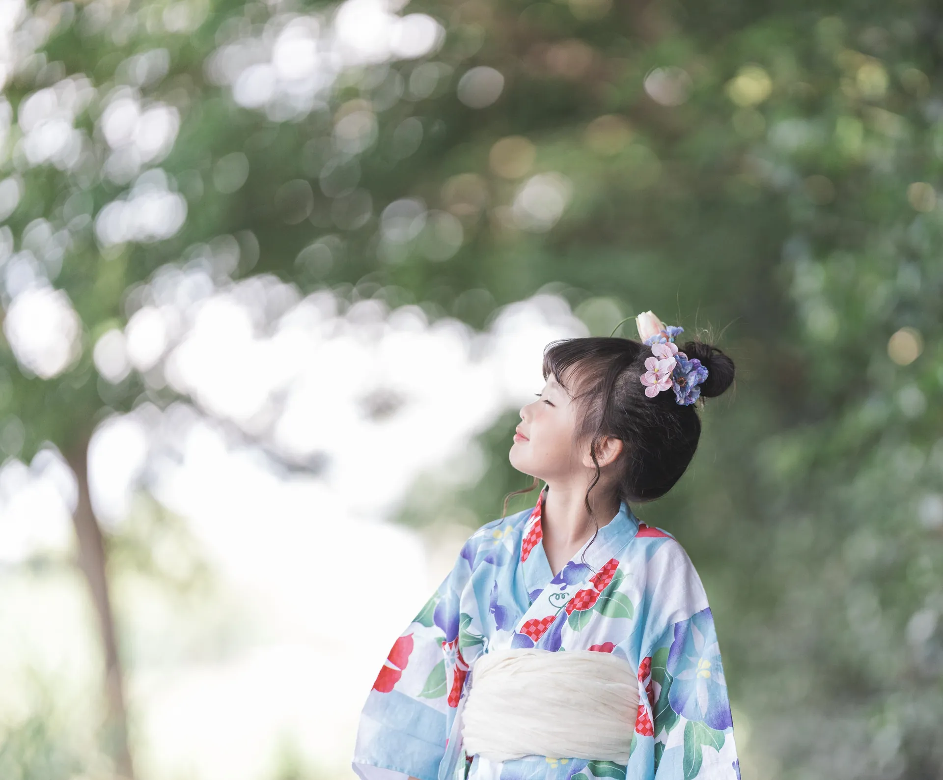 木陰で空を見上げる、浴衣の女の子の写真